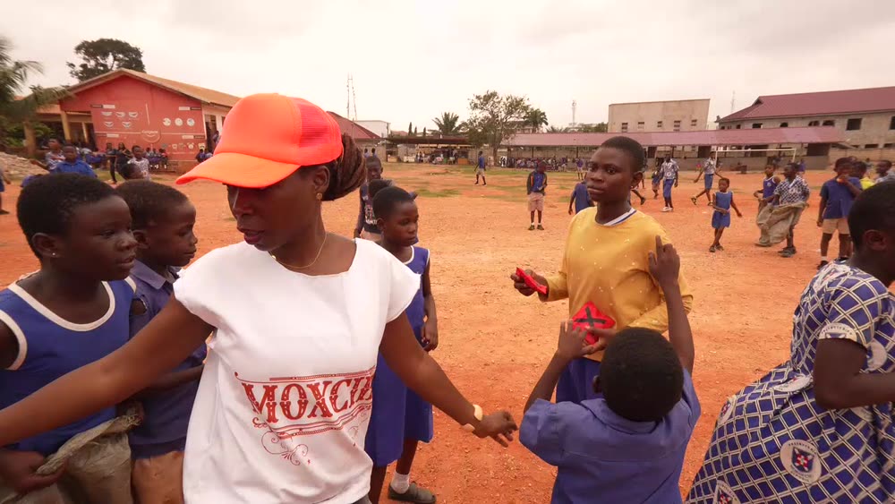 MoxCika scholars linking arms and playing a game at Martey Tsuru Presbyterian school during the July 2026 give back